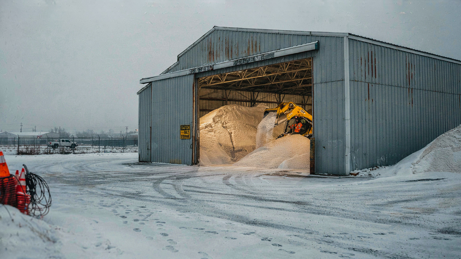 Salt storage barn with road salt stockpiles at a snow operations depot